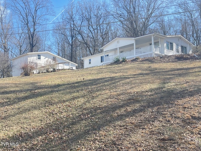 view of side of home featuring covered porch and a yard