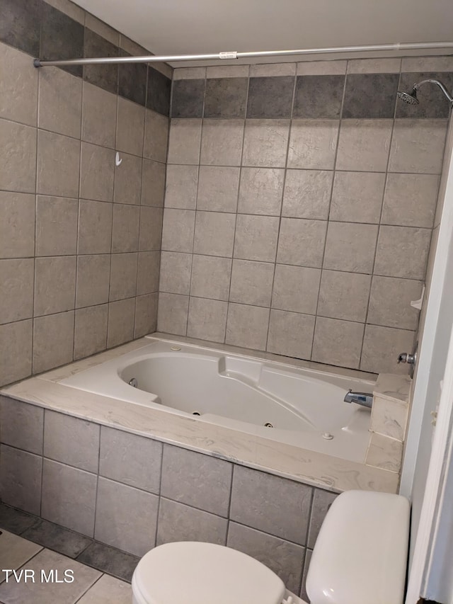 bathroom featuring tiled shower / bath, tile patterned floors, and toilet