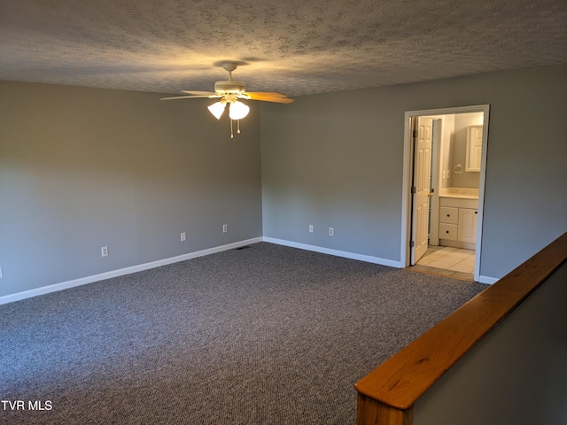 carpeted empty room featuring ceiling fan and a textured ceiling