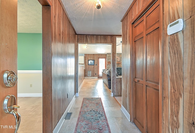 hallway with a textured ceiling and wood walls