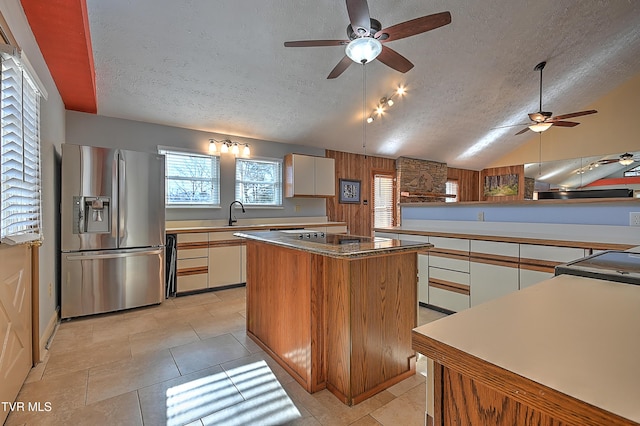 kitchen featuring vaulted ceiling, white cabinetry, a center island, stainless steel refrigerator with ice dispenser, and a textured ceiling