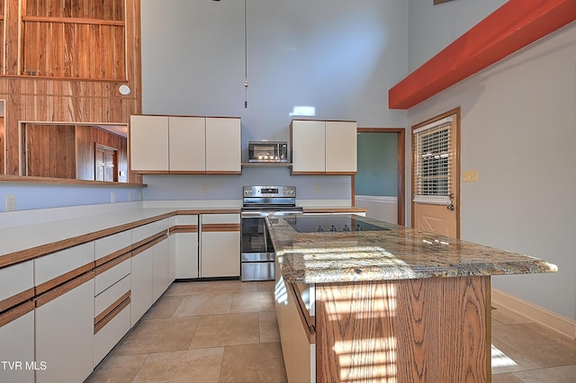 kitchen with stainless steel electric range oven, a kitchen island, and white cabinets