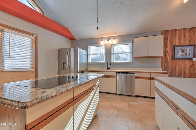 kitchen with sink, white cabinetry, vaulted ceiling, a textured ceiling, and stainless steel appliances