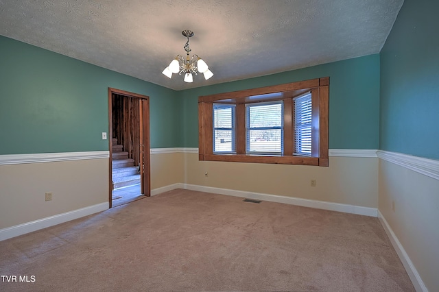 unfurnished room with light carpet, a notable chandelier, and a textured ceiling