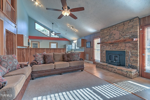 tiled living room featuring a wealth of natural light, a textured ceiling, and wood walls