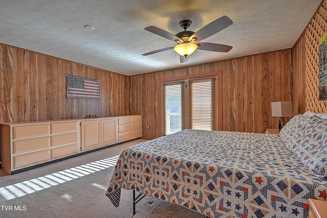 carpeted bedroom with ceiling fan, a textured ceiling, and wooden walls