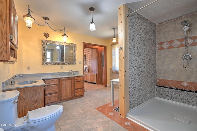 bathroom with vanity, tile patterned flooring, toilet, and a tile shower