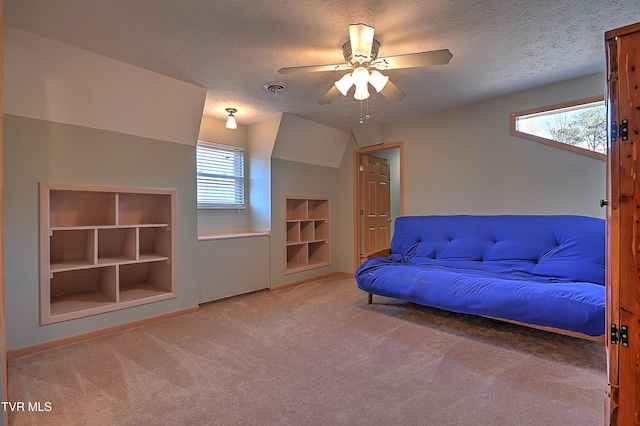 unfurnished room featuring ceiling fan, built in shelves, a textured ceiling, and carpet