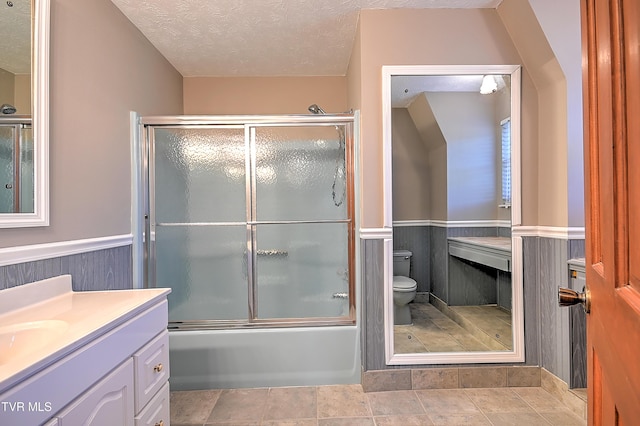 full bathroom with bath / shower combo with glass door, vanity, toilet, and a textured ceiling