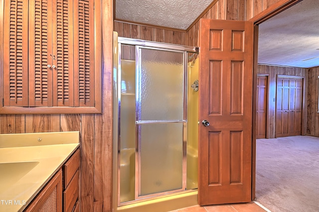 bathroom featuring vanity, a shower with shower door, a textured ceiling, and wood walls