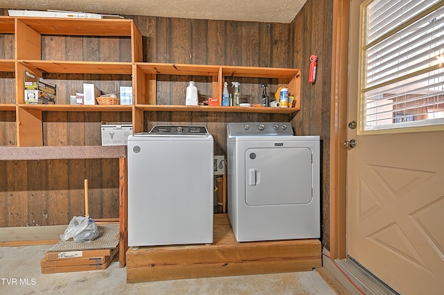 washroom featuring wooden walls, washer and clothes dryer, and a textured ceiling