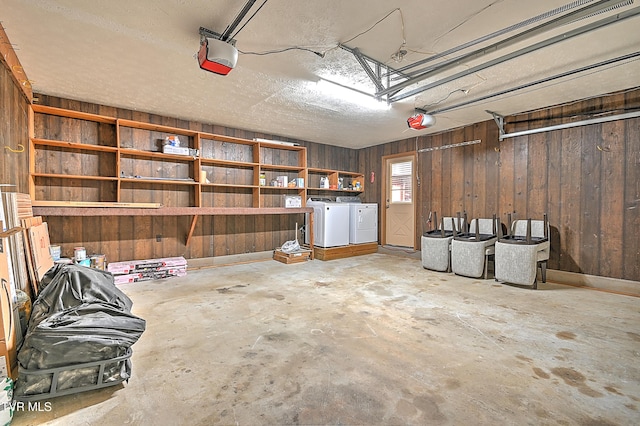 garage featuring washing machine and clothes dryer, a garage door opener, and wood walls