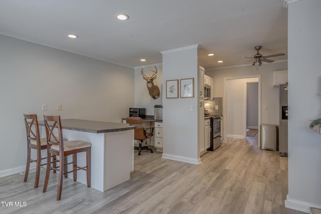 kitchen with tasteful backsplash, appliances with stainless steel finishes, a kitchen breakfast bar, kitchen peninsula, and white cabinets