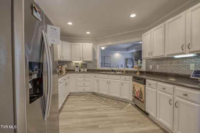 kitchen featuring sink, light hardwood / wood-style flooring, appliances with stainless steel finishes, ornamental molding, and white cabinets