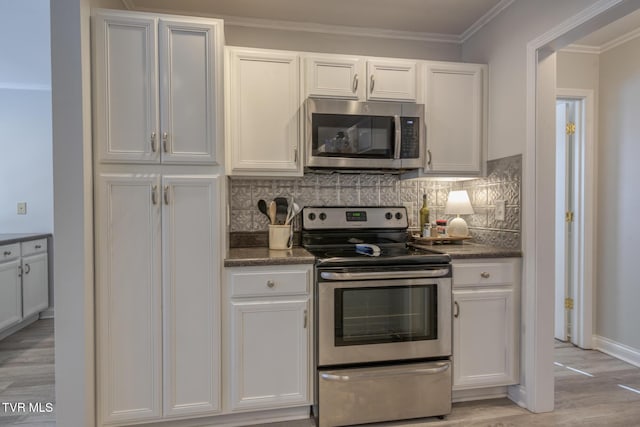 kitchen with appliances with stainless steel finishes, white cabinetry, backsplash, ornamental molding, and light hardwood / wood-style floors