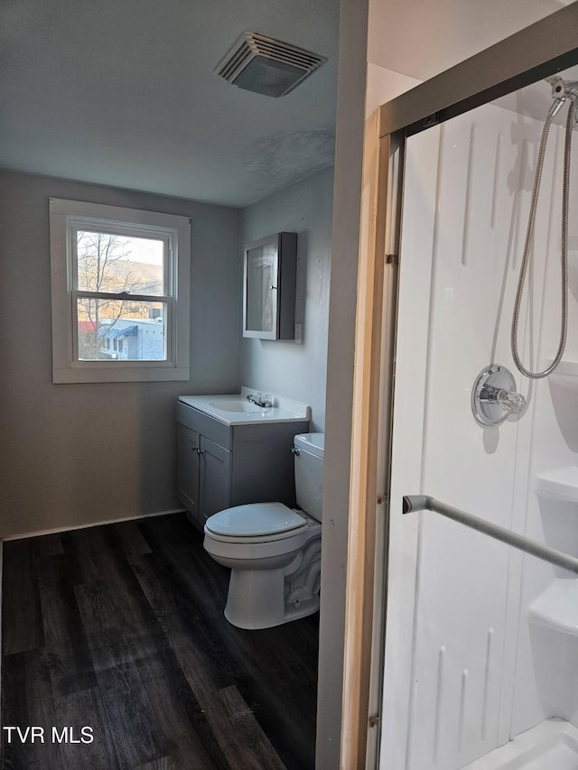 bathroom featuring vanity, toilet, hardwood / wood-style floors, and a shower