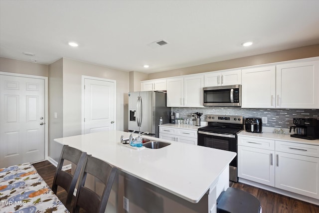 kitchen featuring stainless steel appliances, sink, white cabinets, and a kitchen island with sink