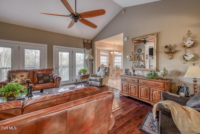 living room featuring ceiling fan with notable chandelier, dark wood-type flooring, and high vaulted ceiling