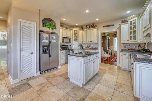 kitchen featuring electric stove, sink, stainless steel fridge, and a center island with sink