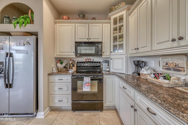 kitchen featuring light tile patterned flooring, dark stone countertops, and black appliances