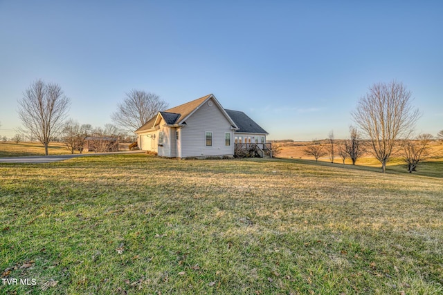 view of property exterior featuring a garage, a yard, and a rural view