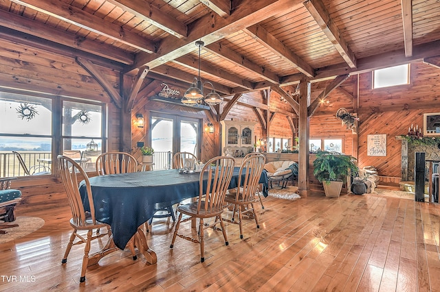 unfurnished dining area with beamed ceiling, wooden ceiling, light wood-type flooring, and wood walls