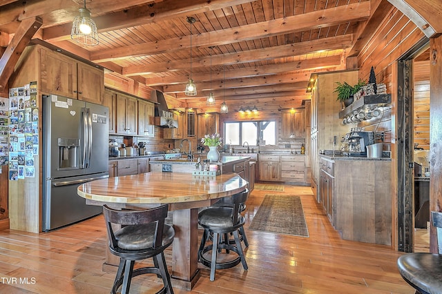 kitchen featuring wood walls, light hardwood / wood-style flooring, wooden ceiling, stainless steel fridge, and wall chimney range hood