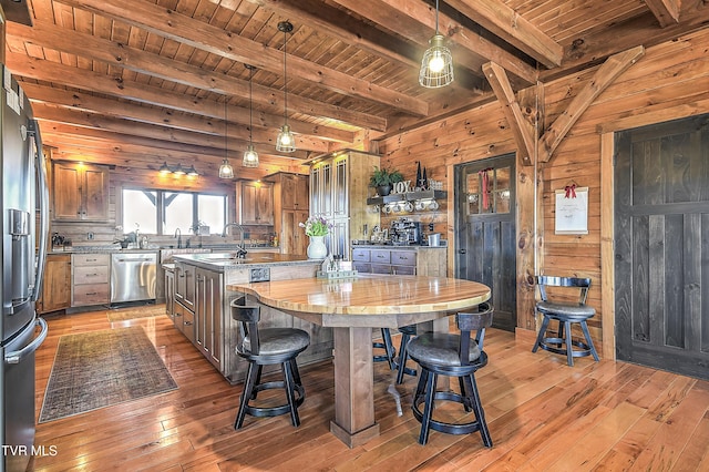 kitchen featuring hanging light fixtures, wood ceiling, stainless steel dishwasher, and an island with sink