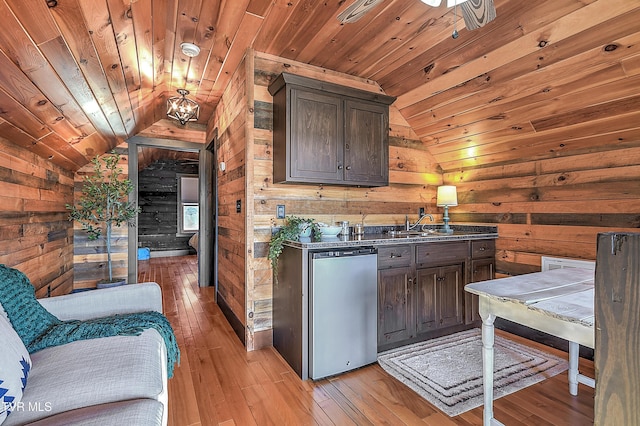 kitchen featuring dark brown cabinets, wooden ceiling, stainless steel refrigerator, light hardwood / wood-style flooring, and wooden walls