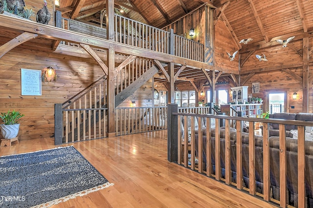 hall with wood walls, wood ceiling, wood-type flooring, high vaulted ceiling, and beamed ceiling