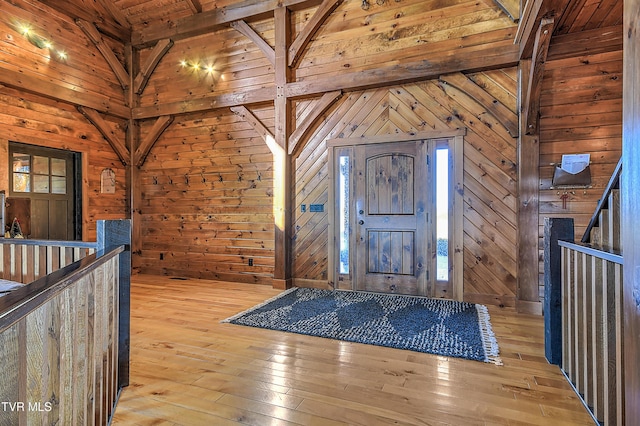 foyer entrance with light hardwood / wood-style flooring and wooden walls