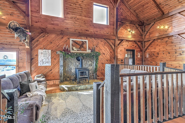 unfurnished living room featuring wood ceiling, hardwood / wood-style floors, wooden walls, high vaulted ceiling, and a wood stove