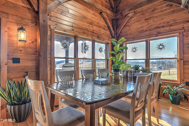 dining space with light hardwood / wood-style flooring, a wealth of natural light, and wood walls