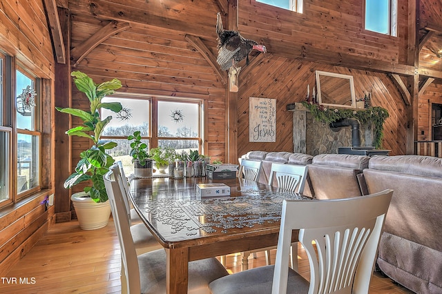 dining space featuring a healthy amount of sunlight, wood-type flooring, a wood stove, and wood walls