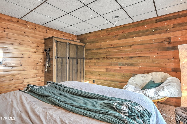 unfurnished bedroom featuring wooden walls and a drop ceiling