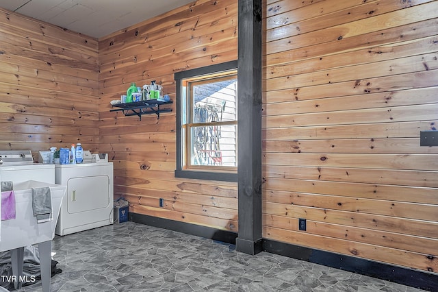 washroom with wooden walls, sink, and washer and dryer