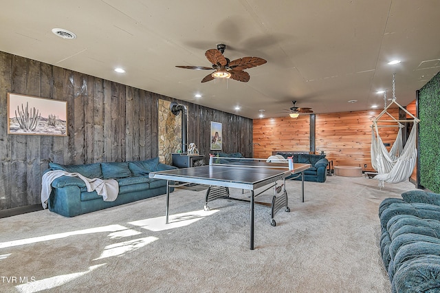 game room with a wood stove, wooden walls, and carpet flooring