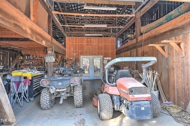 garage featuring a workshop area, wood walls, and french doors