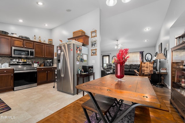 kitchen with ceiling fan, appliances with stainless steel finishes, backsplash, dark brown cabinetry, and light hardwood / wood-style floors