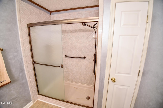 bathroom featuring a shower with shower door, ornamental molding, and a textured ceiling