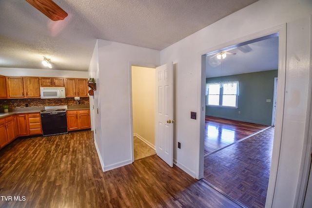 kitchen featuring dark hardwood / wood-style floors, decorative backsplash, range, ceiling fan, and a textured ceiling