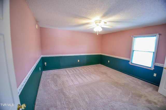 carpeted empty room featuring ceiling fan and a textured ceiling