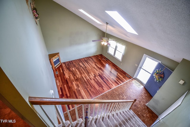 interior space featuring dark parquet flooring, vaulted ceiling with skylight, and a textured ceiling