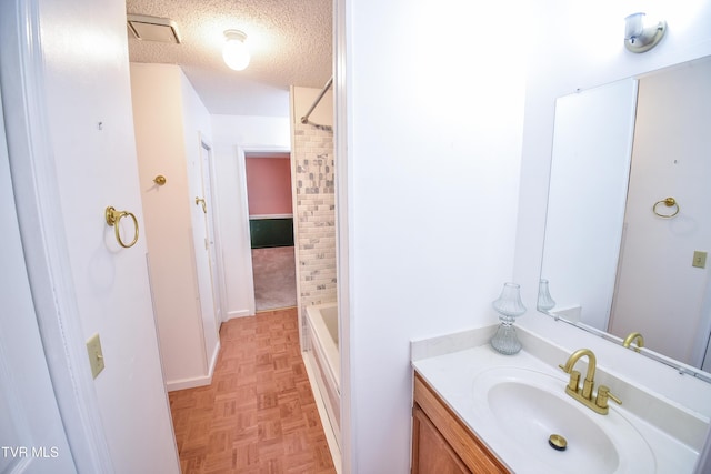 bathroom featuring vanity, parquet flooring, a textured ceiling, and shower / bath combination