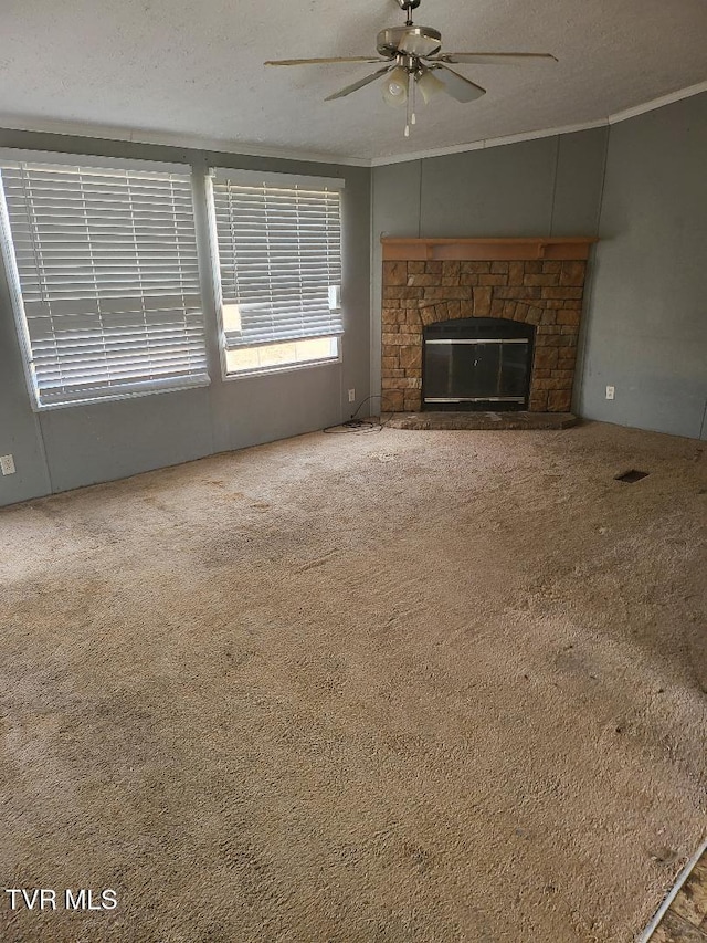 unfurnished living room featuring a textured ceiling, ornamental molding, carpet floors, ceiling fan, and a fireplace