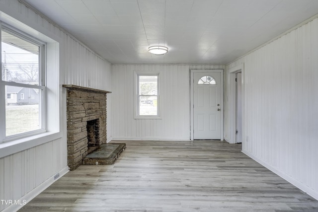 unfurnished living room with a stone fireplace and light wood-type flooring