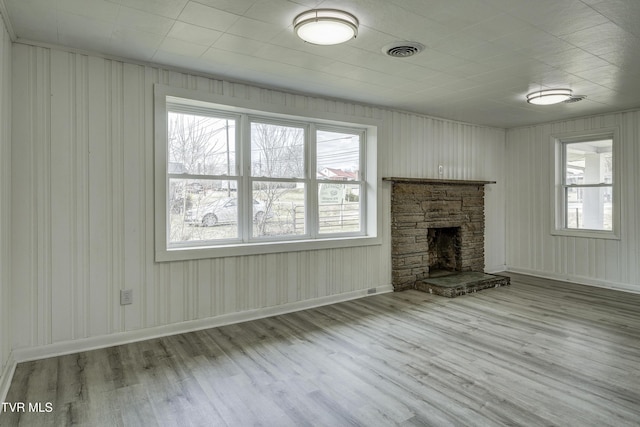 unfurnished living room featuring plenty of natural light, a fireplace, and light hardwood / wood-style floors