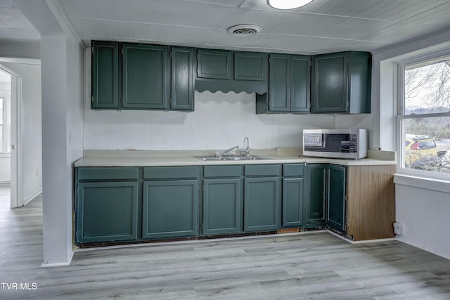 kitchen with sink, light hardwood / wood-style flooring, and green cabinets