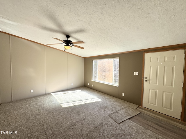 interior space featuring ceiling fan, vaulted ceiling, a textured ceiling, and carpet flooring