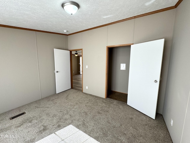 unfurnished bedroom with ornamental molding, carpet, and a textured ceiling